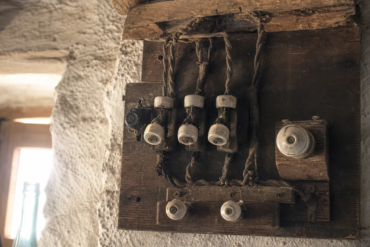 Ancien tableau électrique à fusibles de porcelaine sur mur de pierre dans une maison de pêcheur de Douarnenez